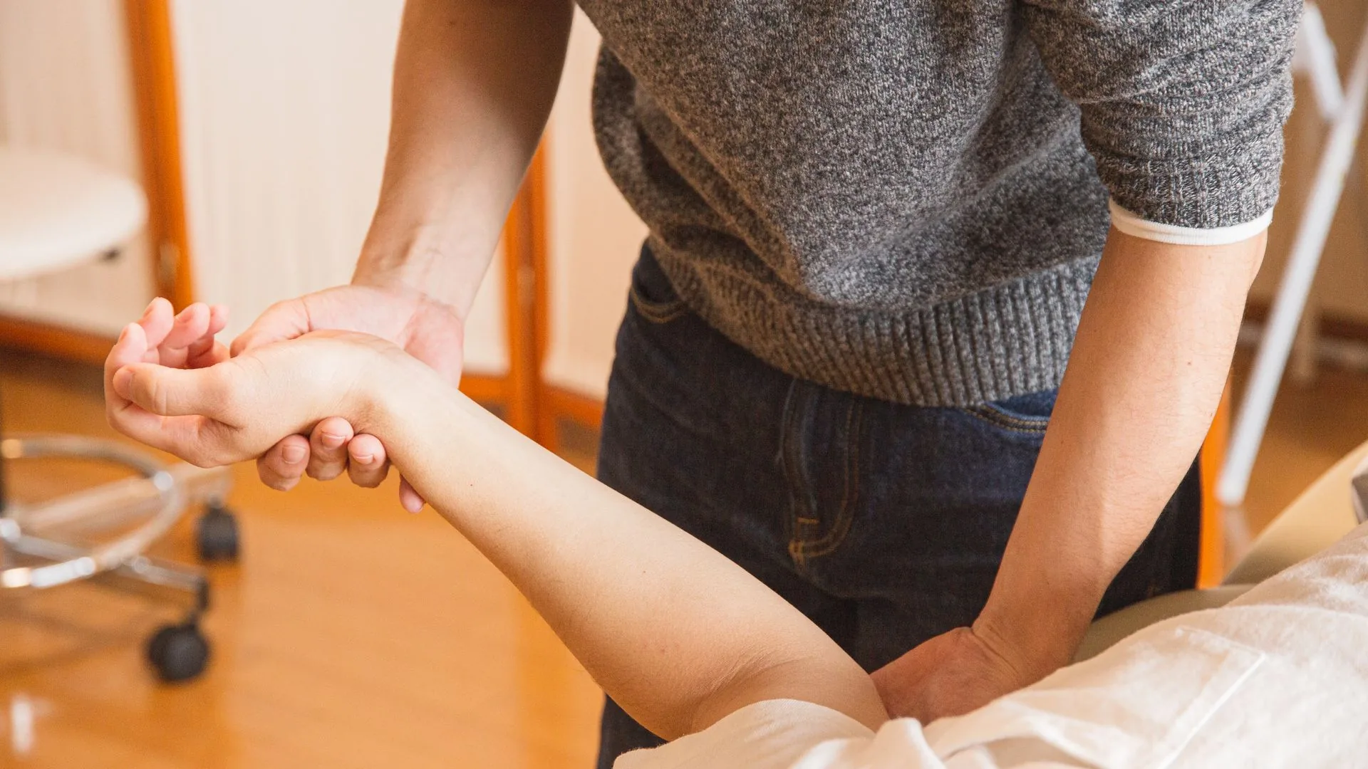A gloved clinician gently turning and examining a patient’s hand and wrist