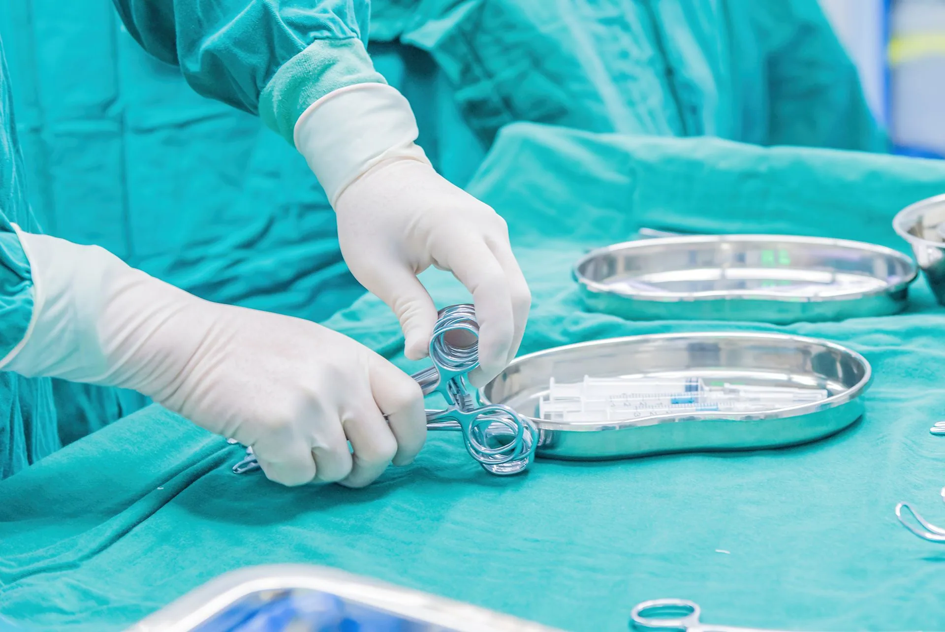 A clinician's gloved hands laying out sterile instruments on a procedure tray