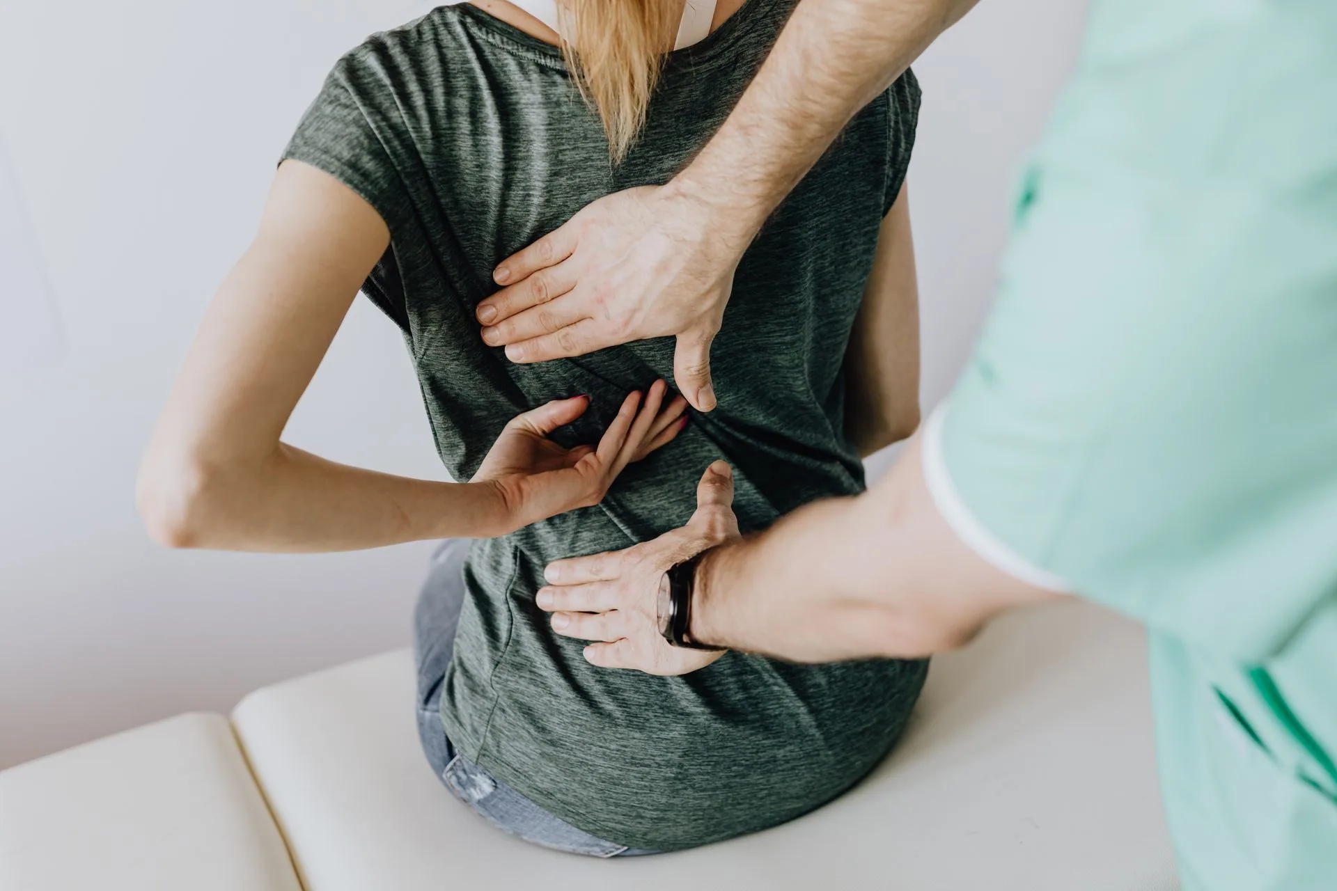 A clinician assessing a seated patient's back by hand
